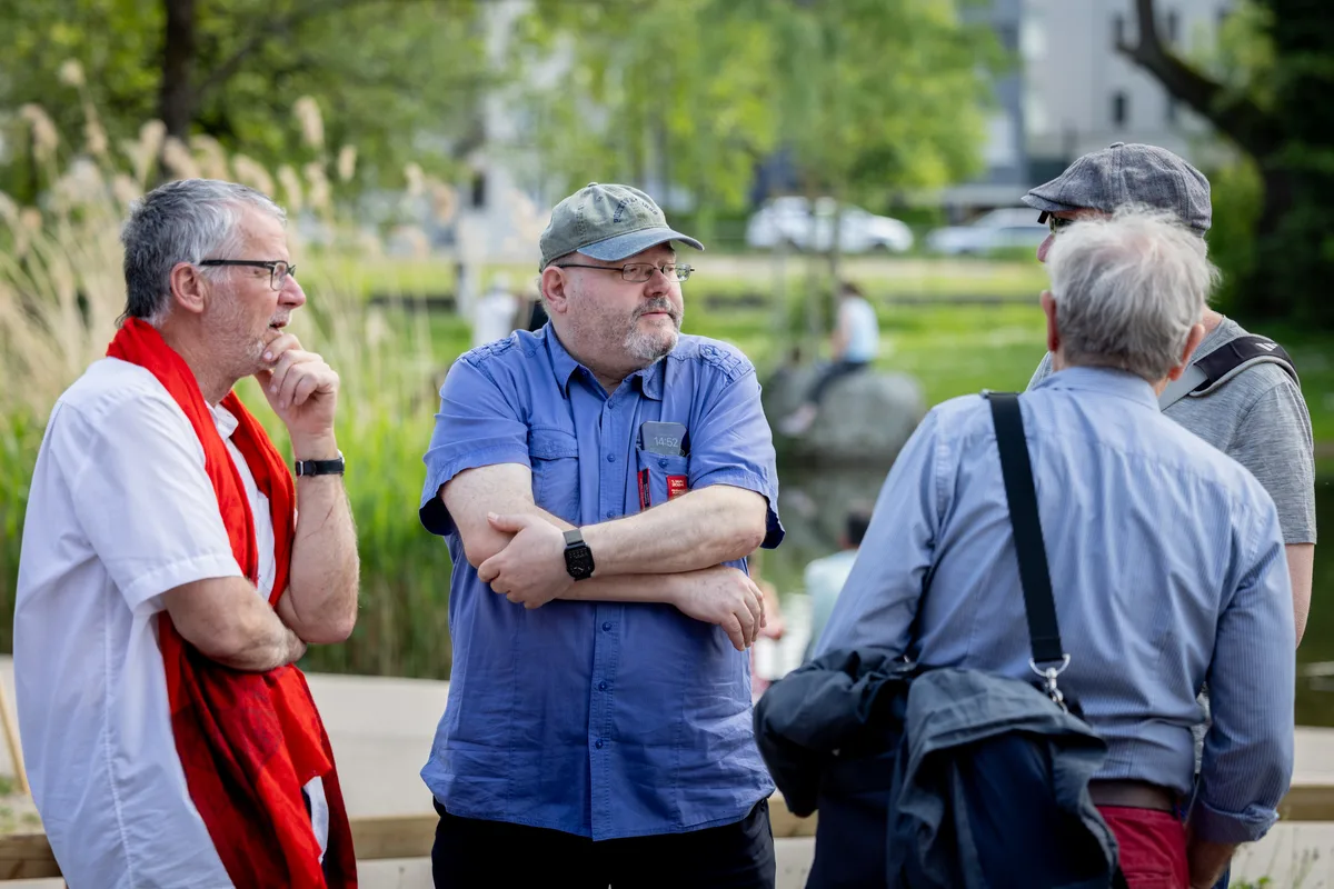 Männer stehen beim Ustermer Stadtpark und sprechen miteinander. 